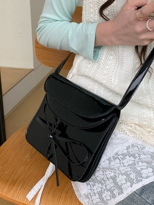 Elegant Black Crossbody Phone Pouch With Glossy Finish And Bow Accent