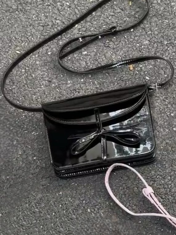 Elegant Black Crossbody Phone Pouch With Glossy Finish And Bow Accent